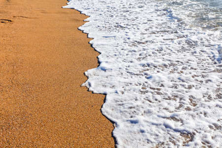 Sun light reflected on soft wave of the sea on the sandy beach