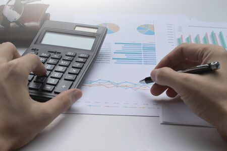 Hand use pen and calculator on the office desk  investment and property for concept. 