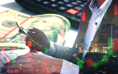 Double exposure of businessman using the laptop with money and stock market or financial graph for...