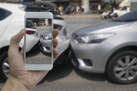Hand holding smart phone take a photo at The scene of a car crash, car accident for insurance.の写真素材