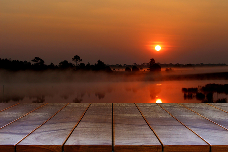 Empty wooden table space platform and blurred Sunset at the lake background for product display montage.の写真素材