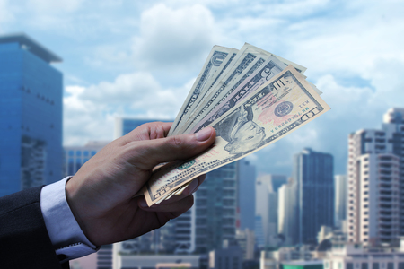 Pay the US dollar on cityscape background.
