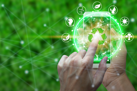 Hand use smartphone with environment Icons over the Network connection on nature background, Technology ecology 
concept.の写真素材