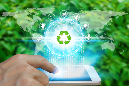Hand use smartphone with environment Icons over the Network connection on nature background, Technology ecology concept.の写真素材
