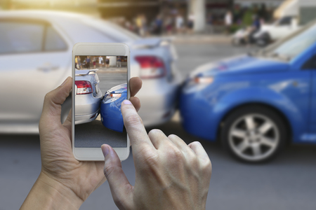 Close up hand holding smartphone and take photo at The scene of a car crash and accident, car accident for car insuranc claim.の写真素材
