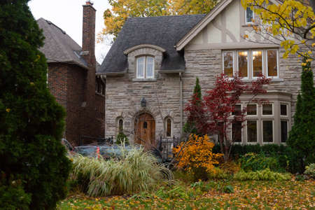 Toronto, ON, Canada - October 25, 2020: Frond side view of a tiny stone house with autumn foliage in the yard.のeditorial素材