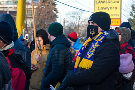Toronto, ON, Canada â€“ February 25, 2022:   Protestors with banners and Ukrainian flags in...