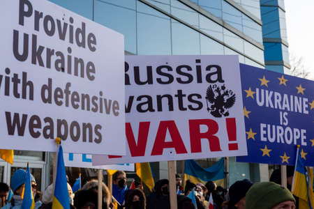 Toronto, ON, Canada â€“ February 25, 2022:   Protestors with banners and Ukrainian flags in...