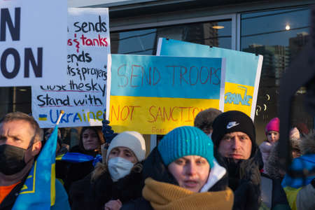 Toronto, ON, Canada â€“ February 25, 2022:   Protestors with banners and Ukrainian flags in...