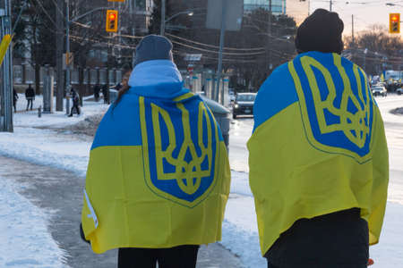 Toronto, ON, Canada â€“ February 25, 2022:   Protestors with banners and Ukrainian flags in...