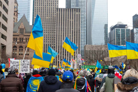 Toronto, Ontario, Canada â€“ February 27, 2022:  Protestors with banners and Ukrainian flags in...