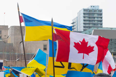 Toronto, Ontario, Canada â€“ February 27, 2022:  Protestors with banners and Ukrainian flags in...
