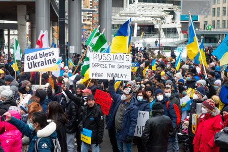 Toronto, Ontario, Canada â€“ February 27, 2022:  Protestors with banners and Ukrainian flags in...