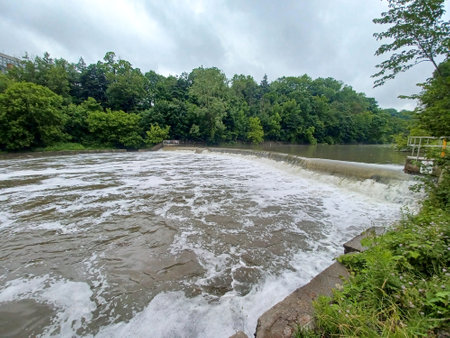 Water flows over a curved concrete salmon ladder on the Humber River, surrounded by dense green forest.の写真素材