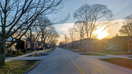 Toronto, ON, Canada - April 9, 2025: A quiet residential street with parked cars and mature trees just starting to bud, reflecting early spring in a quiet neighbourhood.の写真素材