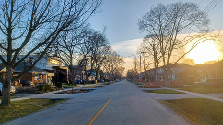 Toronto, ON, Canada - April 9, 2025: A quiet residential street with parked cars and mature trees...