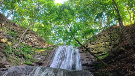 A beautiful waterfall cascades down tiered rock formations in a lush green forest.の写真素材