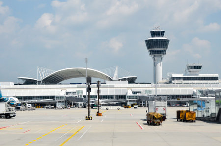 Istanbul, Turkey - August 9, 2008: Munich Airport busy tarmac with the air traffic control tower and modern terminal building under a blue sky, illustrating air travelのeditorial素材