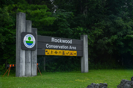 Rockwood, ON, Canada - August 15, 2025: A close-up view of the wooden welcome sign for Rockwood Conservation Area, located near a grassy field and green trees.のeditorial素材