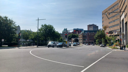 Montreal, QC, Canada - August 7, 2025: Urban street on a sunny day with cars driving and stopped at...