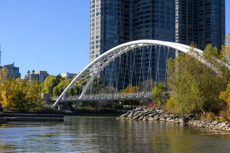 Humber Bay Arch Bridge providing an architectural landmark connecting trails over the Humber River, with Toronto's Etobicoke skyline and colorful autumn trees along the shorelineの写真素材