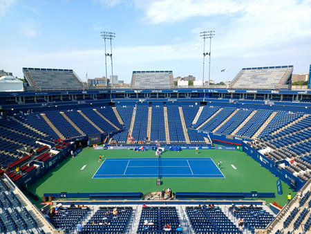 Toronto, ON, Canada - August 23, 2025: A large stadium with rows of empty blue seats surrounds a green tennis court on a sunny dayのeditorial素材
