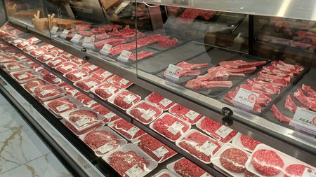 Toronto, ON, Canada - November 25, 2025: Fresh raw meat is stacked and displayed in packages inside a large refrigerated case at a modern supermarket.のeditorial素材