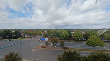Description: Charlotte, NC, USA - October 9, 2025: An elevated view of a suburban road intersection shows traffic, trees, buildings, and a cloudy sky in the background.のeditorial素材