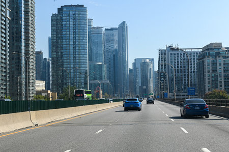 Toronto, Canada - September 30, 2025: Cars drive along a downtown highway with the CN Tower and...