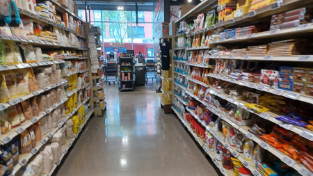 Montreal, QC, Canada - August 1, 2025: A view down a wide, brightly lit aisle in a grocery store with shelves packed full of various food products.のeditorial素材