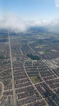 Toronto, ON, Canada - August 29, 2025: The aerial view captures a sprawling cityscape, revealing dense residential areas and infrastructure under a partly cloudy sky.のeditorial素材