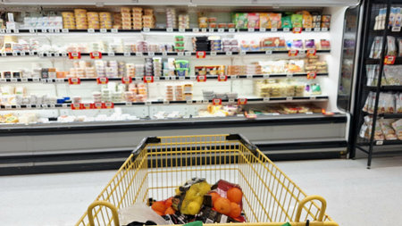 Toronto, ON, Canada - March 13, 2026: A grocery cart contains fruits and vegetables, standing in front of a refrigerated section of a supermarket.のeditorial素材