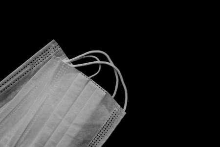 Medical mask for virus protection. Disposable mask. On a black background. Copy space. Two masks are located in the lower left cornerの写真素材