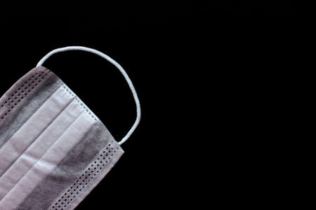 Medical mask for virus protection. Disposable mask. On a black background. Copy space. Mask is located in the lower left cornerの写真素材