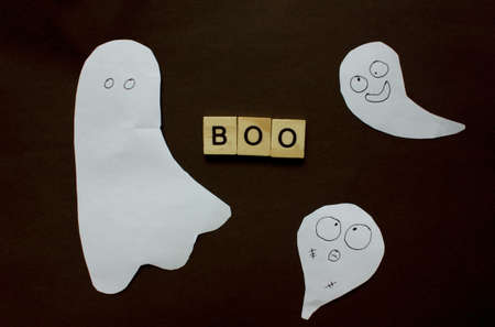 Word Boo. Wooden blocks with an inscription on a black background are decorated with ghosts of paper. The bulletin board. The concept of the holiday is Halluin. View from above. Copy space.の写真素材