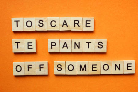 Words Toscare te pants off someone. Wooden blocks with an inscription on an orange background....