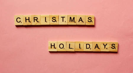 Words Christmas Holidays . Wooden blocks with inscription on pink background. The bulletin board. Concept of holiday-Christmas and New year. View from above. Copy space for text.の写真素材