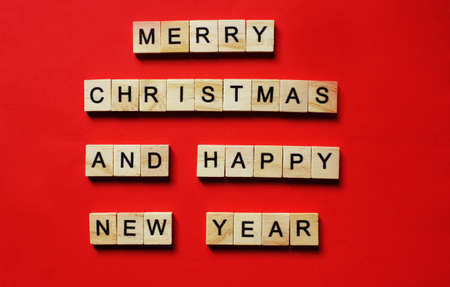 Words Merry Christmas and Happy New Year. Wooden blocks with inscription on red background. The...