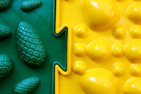 Two orthopedic mats. Bright colorful multicolored mats to prevent flat feet and foot massage. View from above. Orthopedist. Prevention. The yellow and green mat are joined together. Close-up.の写真素材
