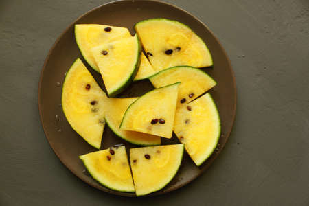 Slices of yellow watermelon on a plate on a black background. Summer concert. A slice of watermelon....