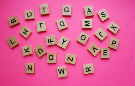 English alphabet. The letters are arranged chaotically on a pink background. View from above. Words. Toy bricks on a pink background. English language. Grammarの写真素材