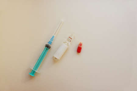 A syringe with needle, vial with medicine, a tablet lie on a light background. Vaccination. The concept of medicine and immunity. Vaccination against viral infections. Copy space. Flatly.の写真素材