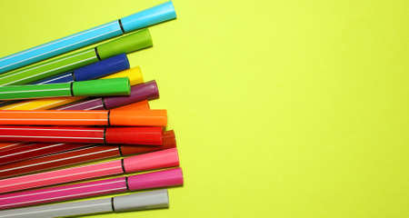Markers of different colors on a yellow background, view from above. Imagination, creativity, art. The markers are on the left. Copy space, Flatly. Bannerの写真素材