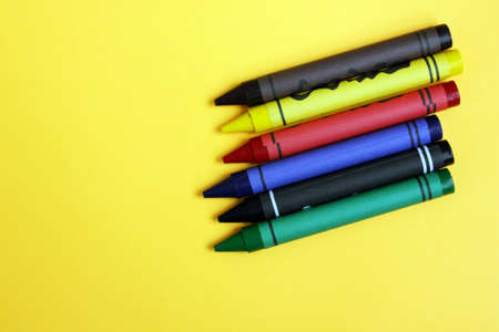 Colored pencils on a yellow background. Lots of different colored wax pencils. Colored pencil....