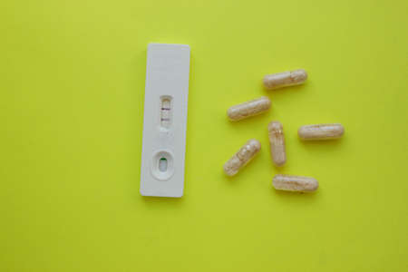positive pregnancy test and pills on yellow background. Vitamins. Motherhood, children, pregnancy,...