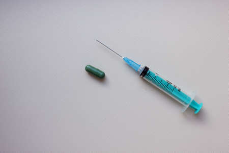 Syringe with needle and tablet on light background. vaccination. concept of medicine and immunity. Vaccination against viral infections. Drug and injection. cold. Injection, drug. Copy space. Flatlyの写真素材