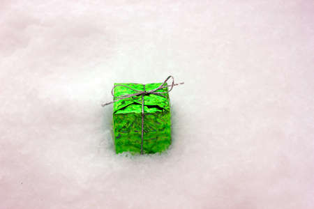 A gift in green paper, isolated on a white background. Gift box. Christmas and New Year. Gift under...