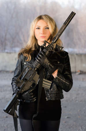 Armed beautiful young woman with a rifle in neglected houseの写真素材