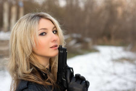 Hot girl holding a gun in winter forestの写真素材