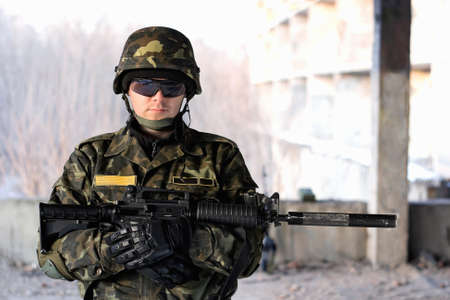 Handsome man with a rifle in front of neglected houseの写真素材